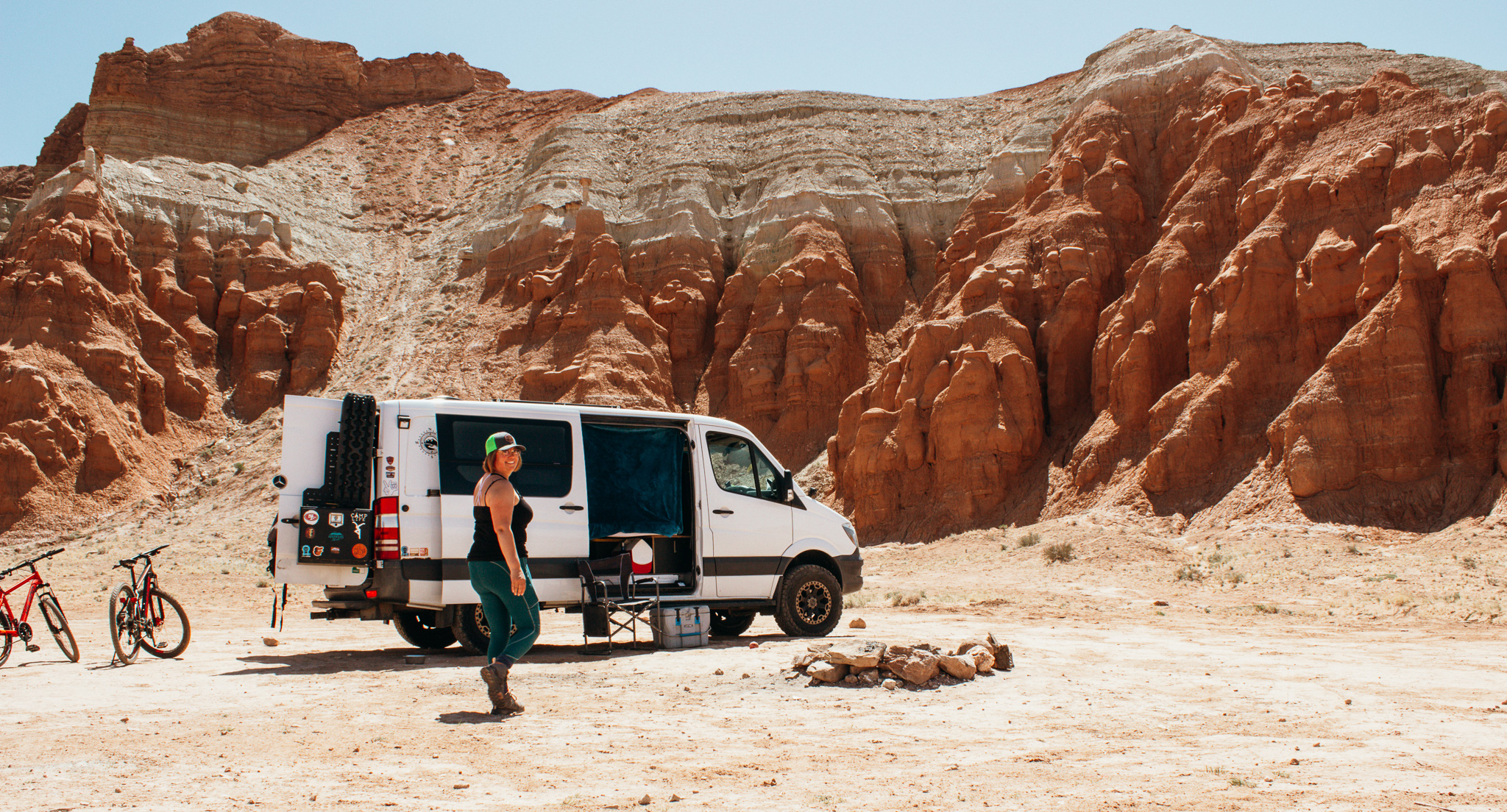 Woman smiling over her shoulder as she walks to her Sprinter van as she boondocks in Utah's San Rafael Swell at Goblin Valley State Park